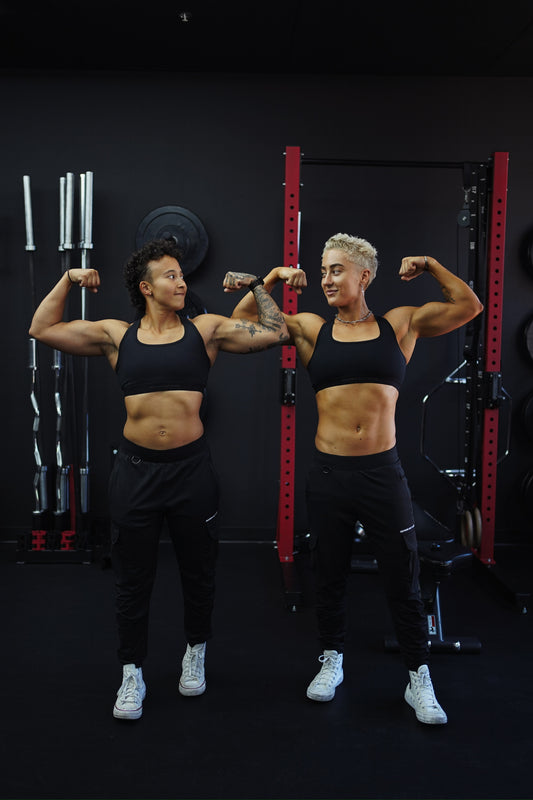two lifters flexing in a gym in front of a red rack