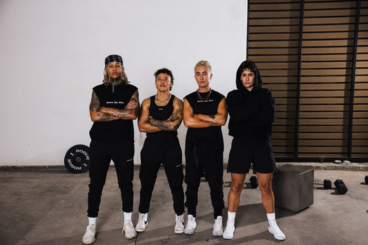 four lifters in black standing shoulder to shoulder in a garage gym