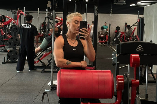 gym floor with red upholstered machines and a lifter in a black tank standing among the equipment